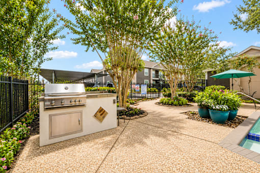 A BBQ grill is in the middle of a landscaped yard.