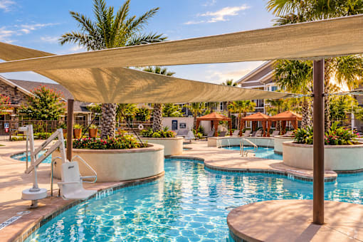 A pool area with a sun lounger and a sun shade.