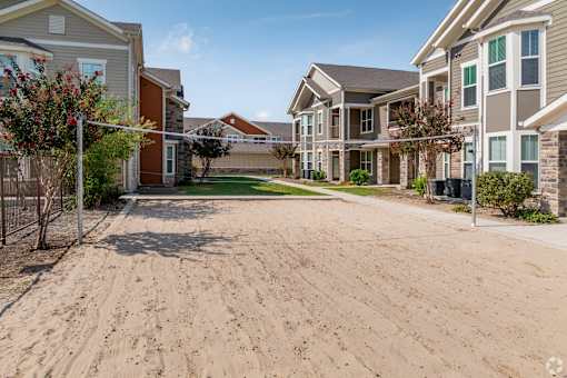 A sandy area in front of a row of houses.