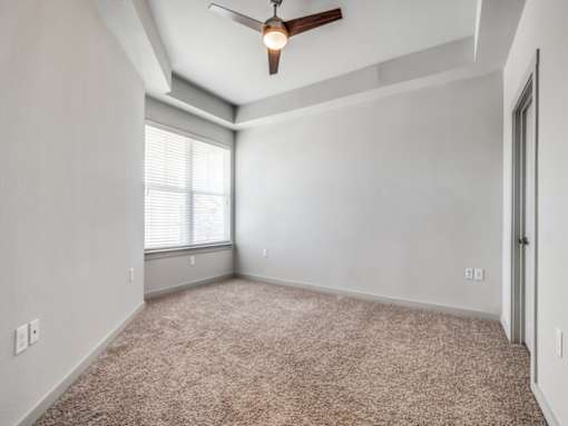 A room with a ceiling fan and carpeted floor.