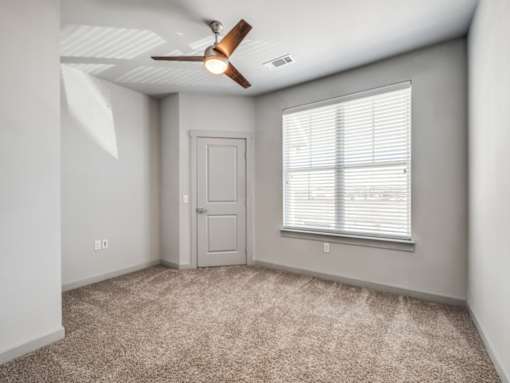 A room with a ceiling fan and a window with blinds.