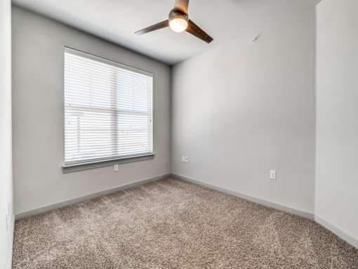 A room with a ceiling fan and a window with blinds.