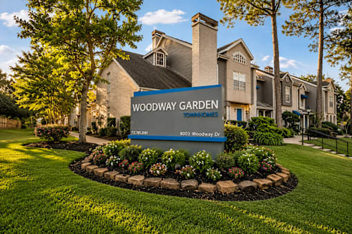 A sign for Woodway Garden in front of a building.
