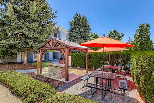 A picnic area with a table and chairs under a red umbrella.