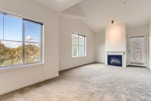 Fairview, OR Apartments for Rent - Lodges at Lake Salish - Living Room with Plush Carpet, an Electric Fireplace, and Large Windows