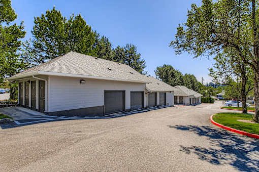 A white building with a grey roof and a parking lot in front.