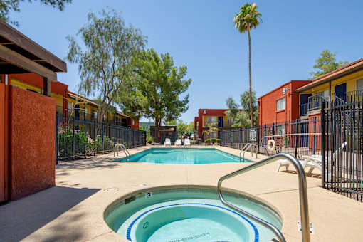 A pool surrounded by red buildings and trees.