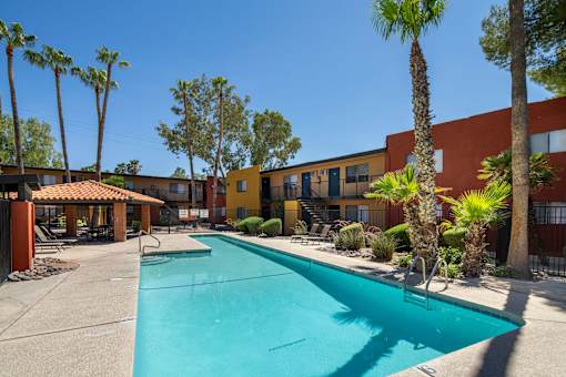 A swimming pool surrounded by palm trees and buildings.