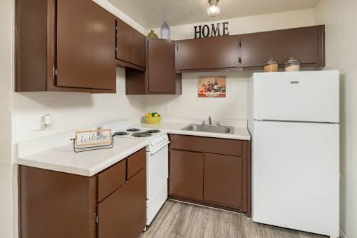 A kitchen with brown cabinets and a white fridge.
