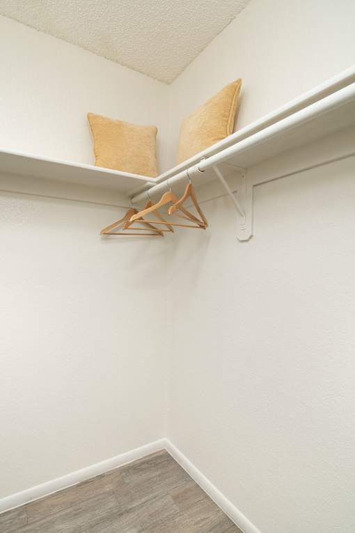 A white shelf with two pillows and a hanger on it.
