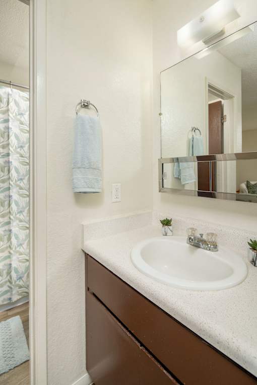 A bathroom with a sink, mirror, and towel.