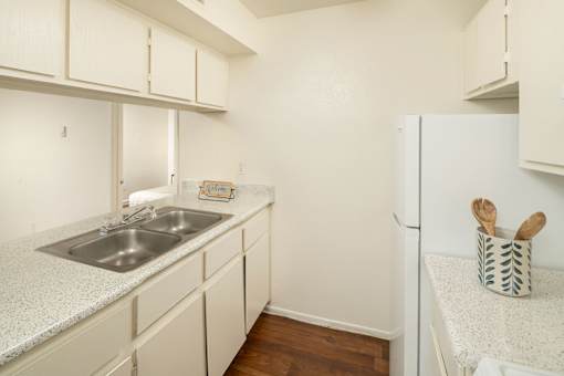 A kitchen with white cabinets and a white fridge.