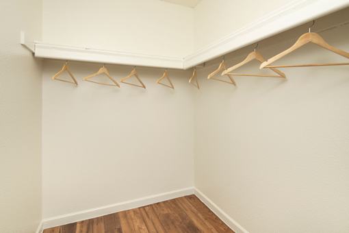 A row of wooden hangers are on a white wall.