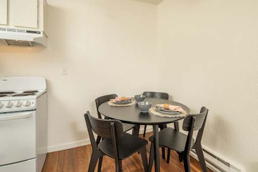A white oven sits next to a table with four chairs.