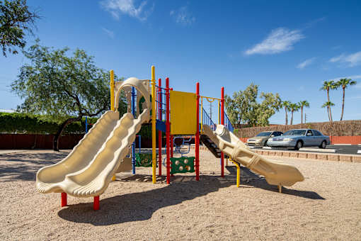 A playground with a yellow slide and a red and yellow structure.