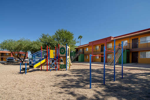 A playground with a slide and swings in front of a building.