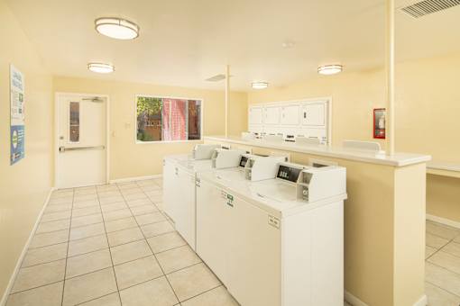 A laundromat with washers and dryers is shown.