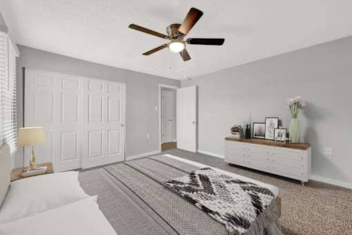 A bedroom with a bed, a dresser, and a ceiling fan.