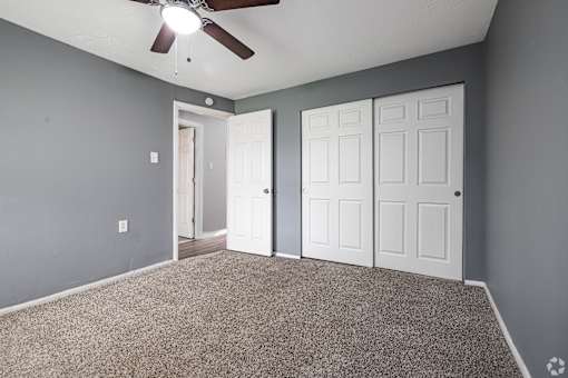 A room with a ceiling fan and two doors.
