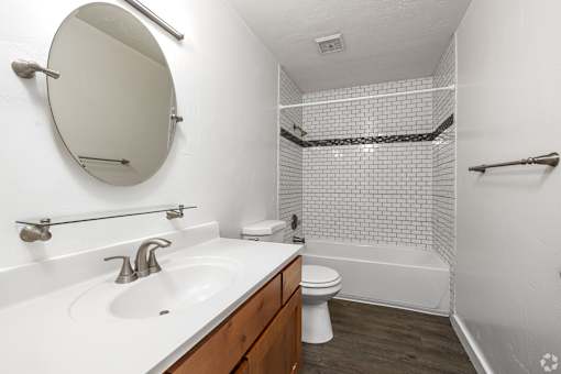 A white sink with a round mirror above it.