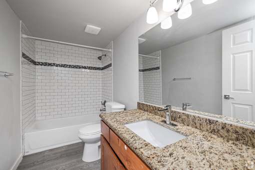 A bathroom with a granite countertop and a white toilet.