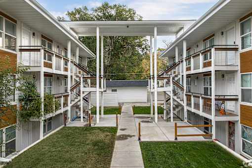 Apartment complex with a white roof and a green lawn.