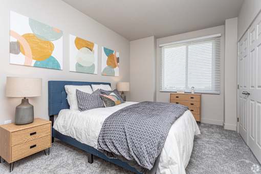 A bedroom with a bed, nightstand, and a painting on the wall.
