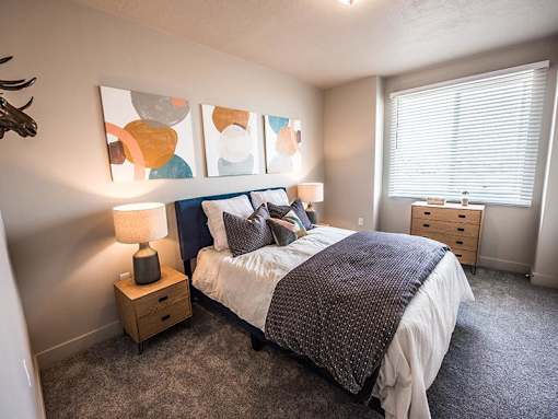 A bedroom with a bed, nightstand, and a deer head on the wall.