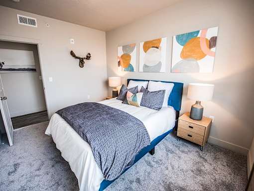 A bedroom with a bed, nightstand, and a painting on the wall.