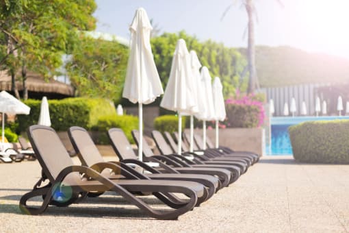 a row of lawn chairs with umbrellas next to a pool