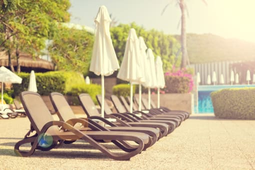a row of lawn chairs with umbrellas next to a pool