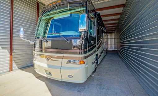 A bus is parked inside a garage with a corrugated metal wall.