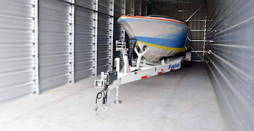 A boat is parked in a garage with a trailer.