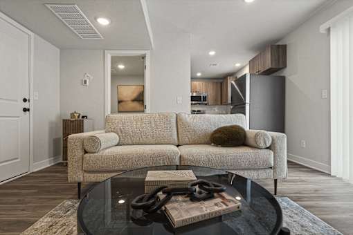 A modern living room with a beige couch and a glass coffee table.