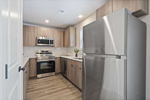 A modern kitchen with a stainless steel refrigerator and wooden cabinets.