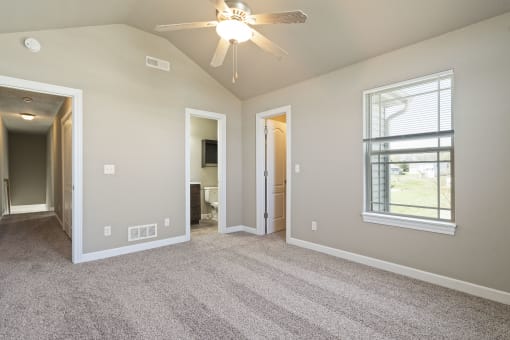 an empty living room with a ceiling fan and a window