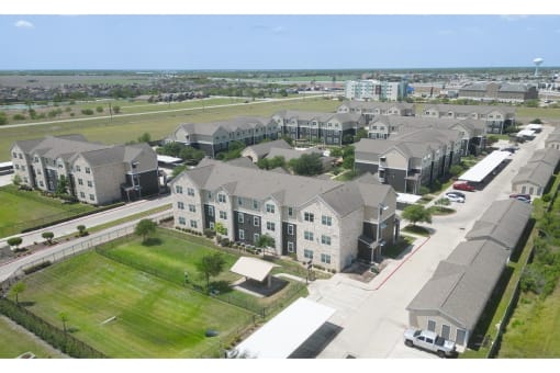 an aerial view of a large housing complex with a grassy field in the foreground