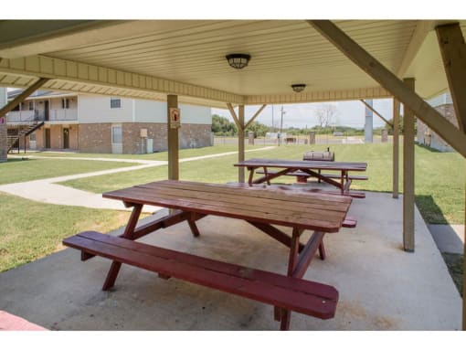 two picnic tables under a shelter in a park