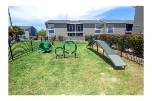 a playground with a slide and chairs in a yard with a building in the background