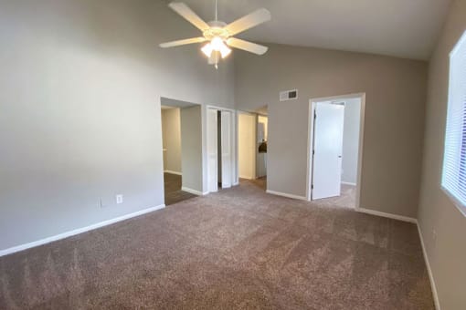 an empty living room with a ceiling fan