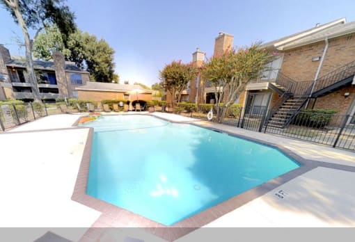 a swimming pool with a fence around it and a brick building in the background