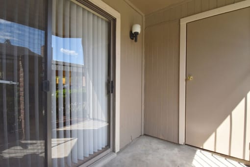 a patio with a sliding glass door and a door to a balcony