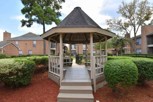 a gazebo with a wooden walkway in front of an apartment building