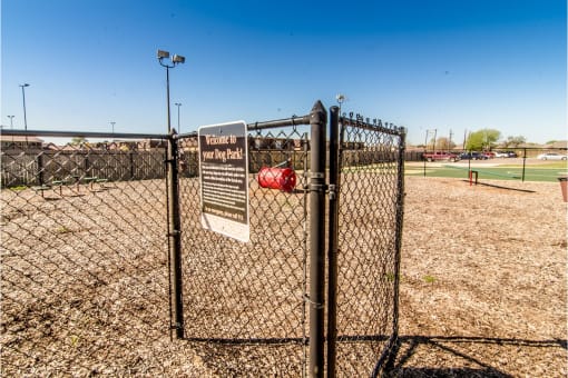 a fence with a sign that says dog park in front of a baseball field