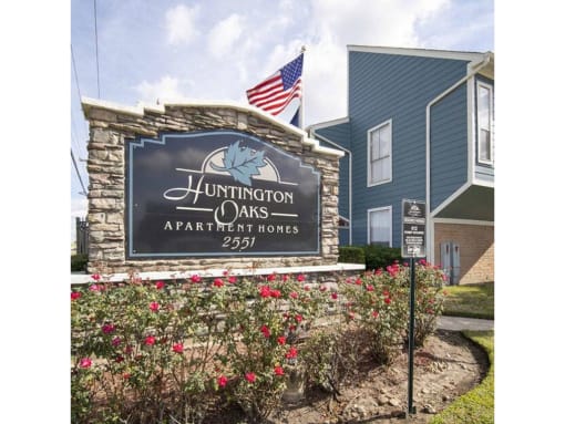 a sign for huntington oaks apartments with an american flag in the background