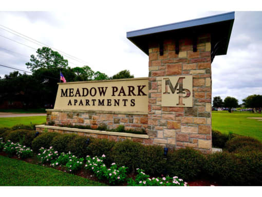 a stone monument with a sign that says meadow park apartments