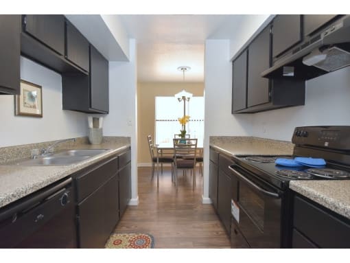 a kitchen with dark cabinets and a table in the background