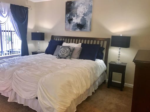 a bedroom with a large bed with a white comforter and blue pillows