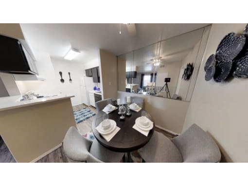 a dining area with a table and chairs and a kitchen in the background