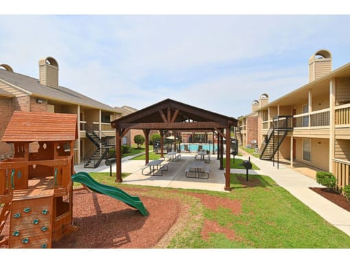 a gazebo with a swing set and a pool in the background